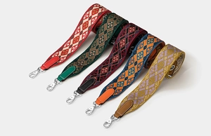 Detailed close-up of embroidered crossbody straps with leather ends and metal lobster clips