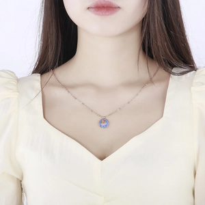 Detail of rose gold necklace with a blue enamel zodiac pendant worn on a collarbone