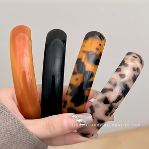 Handheld set of four glossy minimalist acetate spring hair clips in various patterns