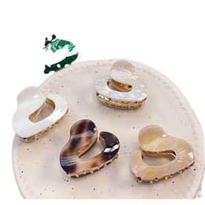 Heart-shaped acetate hair claws in cream white and tortoiseshell on a ceramic tray