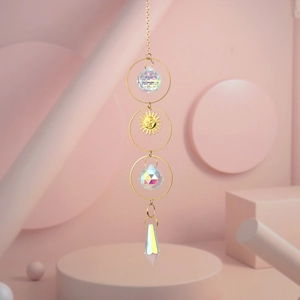 Detail of crystal suncatcher with golden rings and a sun face charm in soft lighting