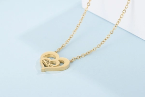 Macro view of gold heart-shaped double pendant with MOM lettering and metallic finish
