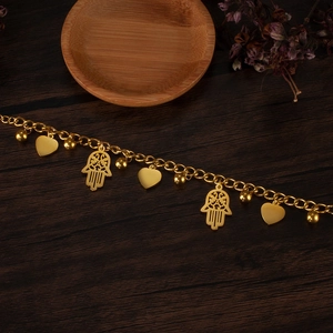Detail of golden Hamsa hand and heart charms on a stainless steel chain bracelet