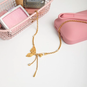 Close-up of 18K gold butterfly necklace with crystal heart pin and tassel details