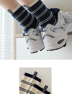 Detail view of navy and beige striped cotton crew socks with ribbed cuffs and woven labels