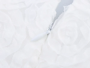 Détail d'une robe en dentelle blanche montrant la fermeture éclair invisible sans couture