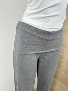 Detail of grey knitted trousers featuring a stylish double-layer fold-over waistband design