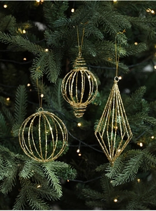 Detail of three geometric hollow gold glitter ornaments hanging on a Christmas tree
