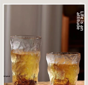 Close-up of two glacier pattern heat-resistant glass cups with golden tea on a wood table