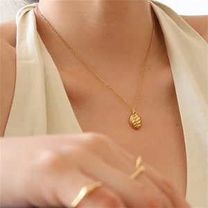 Close-up of twisted oval pendant necklace in gold finish on a female model