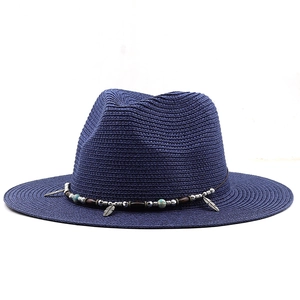Detailed close-up of dark blue straw fedora hat featuring beaded band and silver feather charm