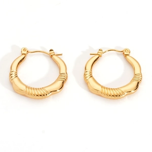 Macro shot of gold stainless steel hoop earrings featuring textured irregular patterns