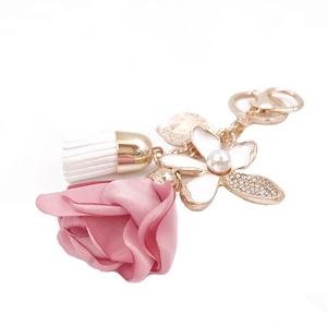 Floral keychain with pink fabric rose, white tassel, and rhinestone clover pendant