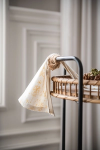 Détail d'une serviette en coton crème avec imprimé flocon doré et étiquette de Noël