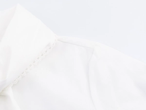 Close-up detail of the elegant crochet lace trim on the white blouse collar and neckline