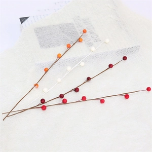 Flat lay of red, orange, and white artificial berry stems for festive floral decoration