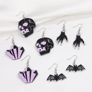 Close-up of gothic Halloween earrings set featuring skull, bat, and bone hand designs