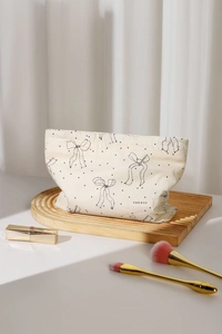Detail of cream canvas makeup bag with black bow patterns and elegant fabric label