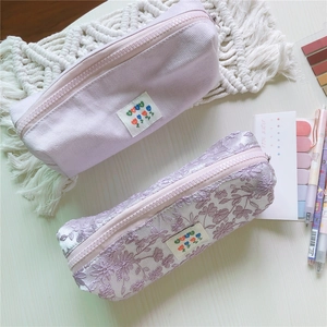 Detalle de estuches de pana y encaje floral violeta claro con etiqueta de BEST