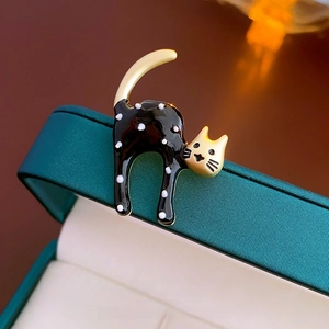 Macro shot of an elegant cat brooch with black enamel, white dots, and gold finish detailing