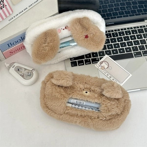 Detail of plush animal-shaped pencil cases in dog and bear designs on a desk