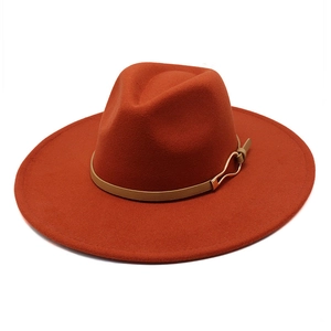 Detailed texture of burnt orange wool fedora hat with brown leather band and gold buckle