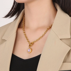 Detail of chunky gold chain necklace with round purple stone pendant and toggle closure