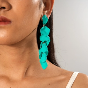 Detail of drop earrings with turquoise irregular petals and gold metal links on a model