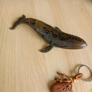 Detailed view of hollow wave pattern on bronze whale incense burner on wooden table