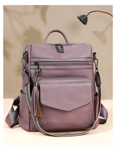 Detail of purple faux leather backpack featuring a colorful woven tassel shoulder strap