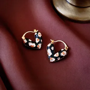 Boucles d'oreilles créoles coeur dorées avec émail léopard sur fond de velours rouge