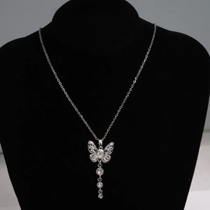 Détail du pendentif papillon argenté avec zircons en cascade sur un mannequin en velours