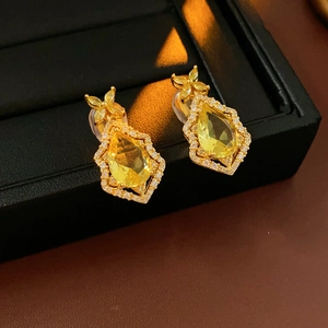 Macro shot of gold teardrop earrings with yellow stones in a black jewelry box