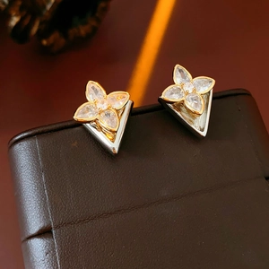 Macro shot of gold four-leaf clover earrings with sparkling cubic zirconia on leather box