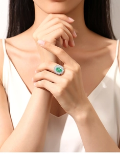 Detail shot of a luxury S925 silver ring featuring a large oval emerald and halo diamonds