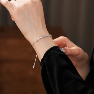 Close-up of adjustable silver clover bracelet with sparkling cubic zirconia on wrist