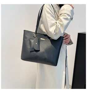 Detail of black pebbled leather tote bag with a small hanging coin purse and gold hardware