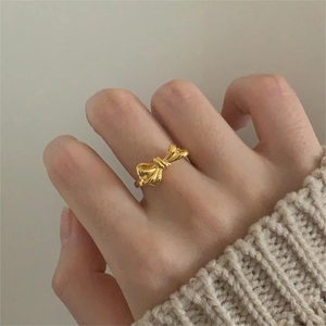Close-up of elegant gold bow ring on finger with soft knit sweater background