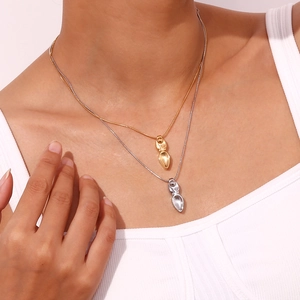 Gros plan de colliers superposés en or et argent avec des pendentifs géométriques abstraits