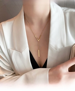 Detail of elegant gold V-shaped pendant necklace with polished metal bar on neck