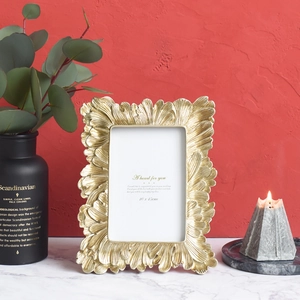 Vintage golden leaf embossed photo frame on marble table with a warm ambient background