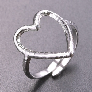 Macro detail of silver heart-shaped ring featuring a textured hammered finish and open band