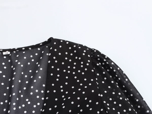 Detailed view of black polka dot dress with V-neckline and white S size label