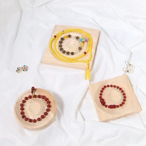 Top view of assorted beaded bracelets and earrings on a natural wood display tray