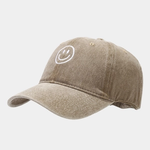 Detail of vintage washed khaki baseball cap featuring white embroidered smiley face