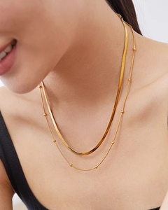 Detail of double-layer golden snake chain and bead necklace worn on neck