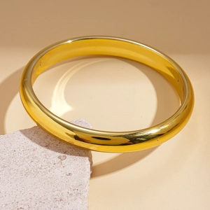 Macro detail of polished gold geometric round cuff bracelet on pink decorative stone
