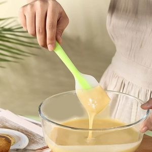 Silicone spatula stirring batter in a glass bowl for professional cake baking