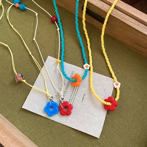 Detailed flat lay of colorful handmade beaded flower necklaces on textured background