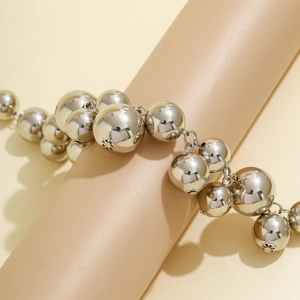 Detail of silver beaded multi-strand bracelet with metallic spheres on a soft background